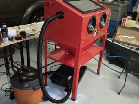 1994 Ford Bronco - A red sandblaster cabinet is set up with a shop vac and various tools on a workbench.