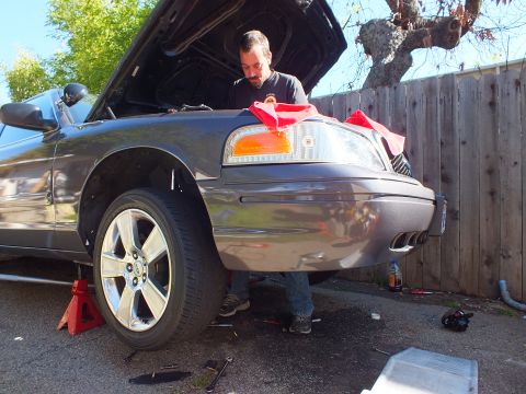 2003 Ford Crown Victoria - Front quarter of a gray sedan on a red jack stand, alloy wheel and amber turn signal in view.