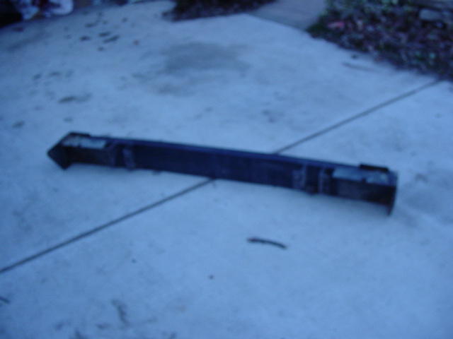 Black bumper lying on concrete, showing mounting brackets and damage