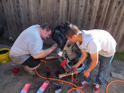 2003 Ford Crown Victoria - Backyard engine teardown with two mechanics, pneumatic tools and oil cans laid out on the pavement