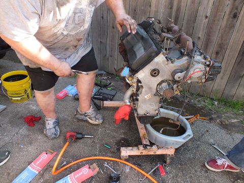 2003 Ford Crown Victoria - Removing a cover from a stripped engine block staged on wood, yellow bucket and tools nearby