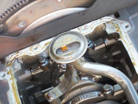 2003 Ford Crown Victoria - Engine oil pickup screen and tube exposed on a SOHC block, flywheel ring gear at left