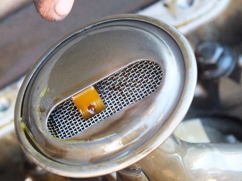 2003 Ford Crown Victoria - Macro of an oil pump pickup screen showing trapped orange debris in the wire mesh