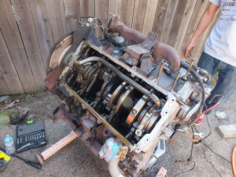 2003 Ford Crown Victoria - Stripped engine block with crankshaft and exhaust manifolds, socket set on the ground