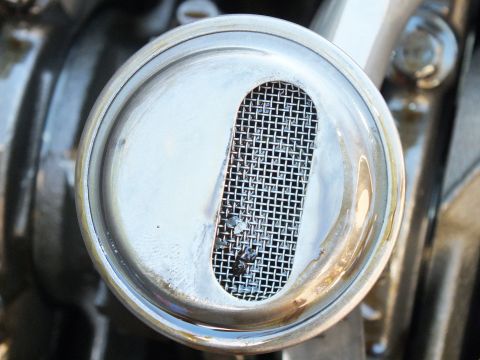 2003 Ford Crown Victoria - Oil pickup strainer screen close-up showing trapped debris across the mesh slot