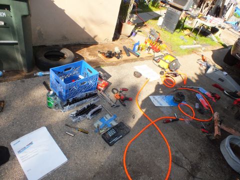 2003 Ford Crown Victoria - Overhead view of a teardown workspace with tools, parts crate and coiled orange air hose
