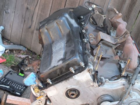2003 Ford Crown Victoria - Oil pan fitted to the underside of an engine block, socket set and bolts staged nearby