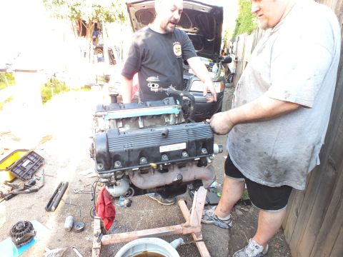 2003 Ford Crown Victoria - Engine showing valve covers on a homemade stand as two men work near an open vehicle hood