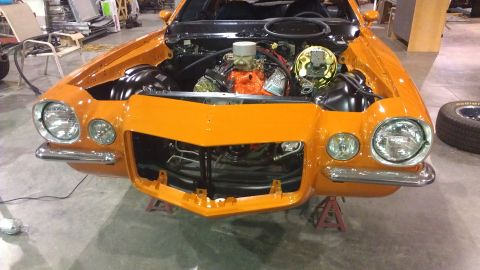 1973 Chevrolet Camaro - Front view of an orange 1973 Chevrolet Camaro with its hood open, revealing the engine and front suspension.