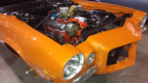 1973 Chevrolet Camaro - The front end of an orange 1970 Chevrolet Camaro is shown with its hood open, revealing the engine.