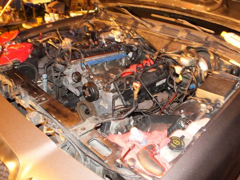2003 Ford Crown Victoria - Top-down look into a partially disassembled engine compartment showing a blue valve cover and tangled wiring.