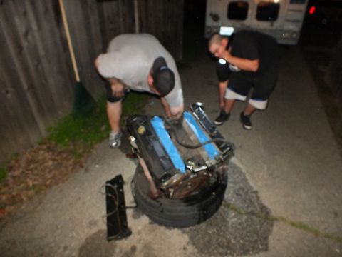 2003 Ford Crown Victoria - Nighttime backyard engine teardown, a V6 propped on a tire while two men work under flashlight