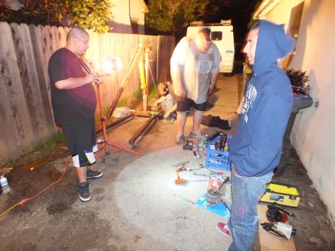 2003 Ford Crown Victoria - Group of men gather around tools and parts laid out on the ground during a late-night repair