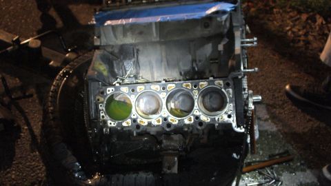 2003 Ford Crown Victoria - Four-cylinder block stripped to bare bores with green coolant pooled, photographed top-down at night