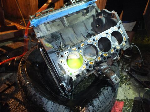 2003 Ford Crown Victoria - Stripped engine block on a tire shows open bores and head gasket with green coolant collected inside