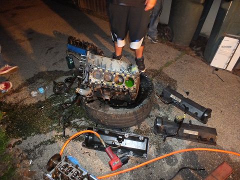 2003 Ford Crown Victoria - Stripped block on a tire surrounded by removed valve covers, an impact wrench and scattered tools