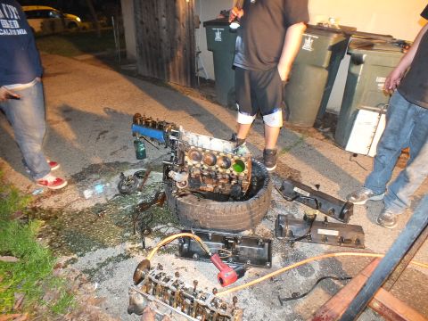 2003 Ford Crown Victoria - Nighttime driveway engine teardown with valve covers, head and components laid out beside trash bins