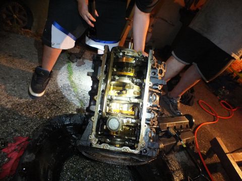 2003 Ford Crown Victoria - Disassembled engine on a tire with crankshaft, caps and timing chain visible under light