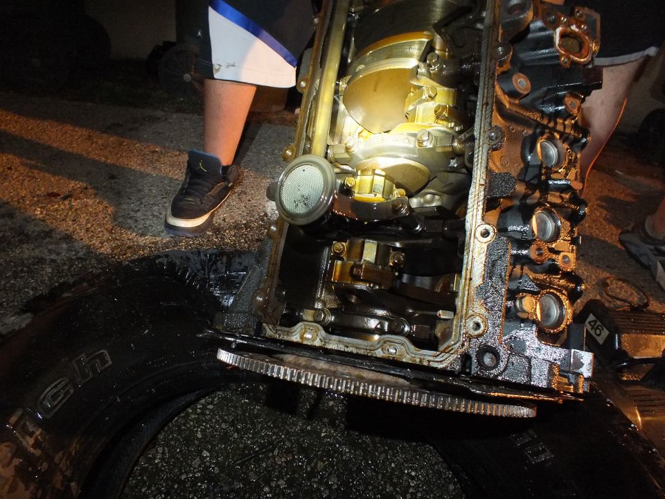 Close view of engine block crankshaft journals and rods on a tire at night