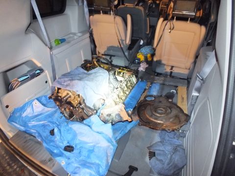 2003 Ford Crown Victoria - Pulled engine assembly and flexplate laid out on a blue tarp covering the floor of a minivan cabin