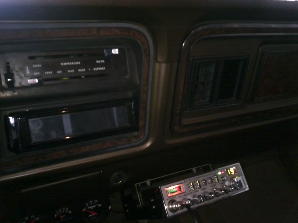 Car interior showing climate controls, a car stereo, and a CB radio with a digital display showing '19'