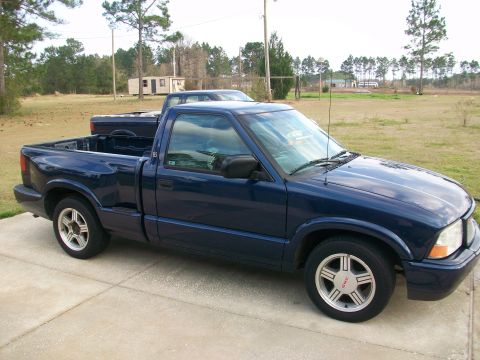 2000 GMC Sonoma - A blue pickup truck is parked on a concrete driveway with another vehicle in the background.