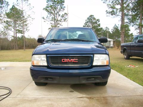 2000 GMC Sonoma - A blue 2000 GMC Sonoma pickup truck is shown from the front, with another truck in the background.