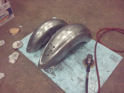 1995 Ford F-150 - Two unpainted metal motorcycle fenders are prepared for finishing with a sander and air hose nearby.