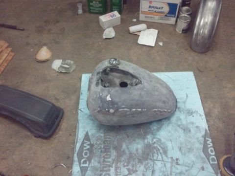 1995 Ford F-150 - A gray, unfinished motorcycle gas tank sits on a blue foam board in a workshop setting.