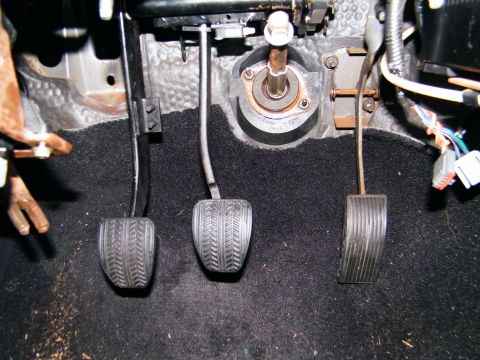 2004 Ford Crown Victoria - Close-up view of the driver's side footwell showing the clutch, brake, and accelerator pedals.