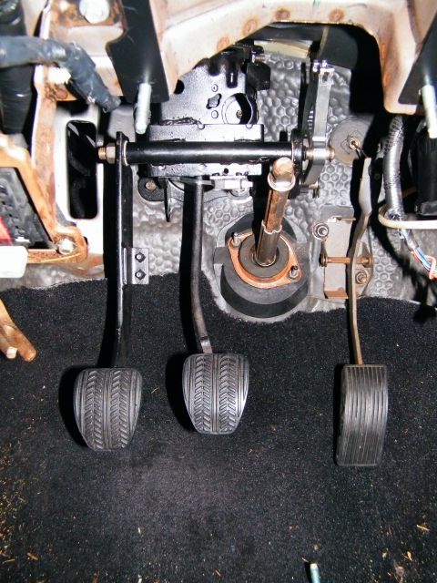 2004 Ford Crown Victoria - Close-up view of the driver's side foot pedals and steering column assembly.