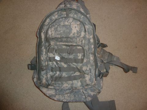 1992 Ford Mustang - A digital camouflage backpack lies on a carpeted surface, showing its various pockets and straps.