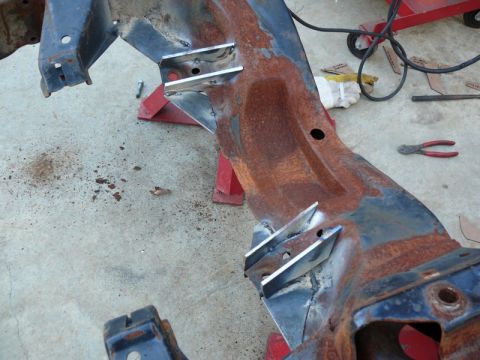1976 Chevrolet Corvette - A section of a heavily rusted vehicle frame shows newly welded metal brackets, indicating repair or modification work.