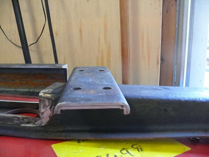 Metal bracket with four bolt holes, held in a vise