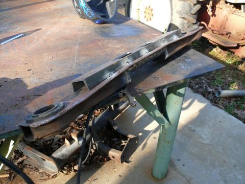 1976 Chevrolet Corvette - A metal suspension component rests on a workbench, with a welding helmet visible in the background.