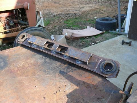 1976 Chevrolet Corvette - Fabricated metal part with bushings sits on a workbench next to a tractor.
