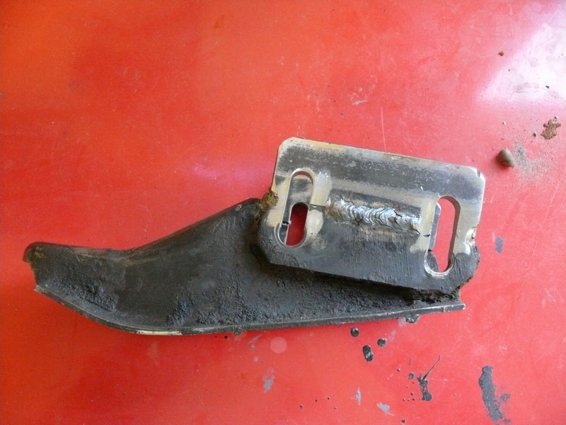 metal bracket with two slots, welded metal, on red surface
