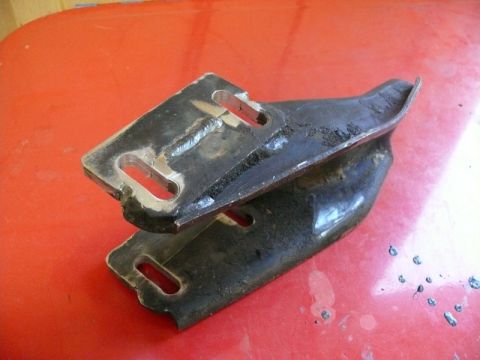 1976 Chevrolet Corvette - A metal bracket, likely a car part, is shown close-up on a red background.
