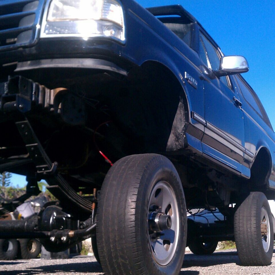 Black 1995 Ford Bronco lifted with large tires, viewed from a low angle