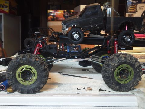 1985 Ford Bronco - A custom-built RC truck chassis with a black pickup body is displayed, with another RC vehicle frame visible in the background.