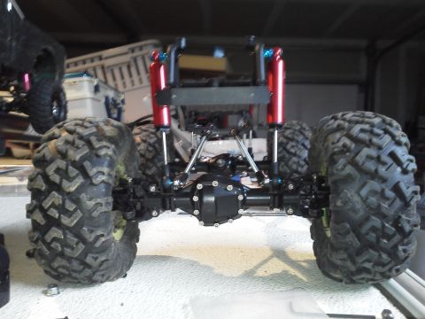 1985 Ford Bronco - The rear suspension and axle assembly of a custom remote control monster truck is visible, with large off-road tires and bright red shock a…