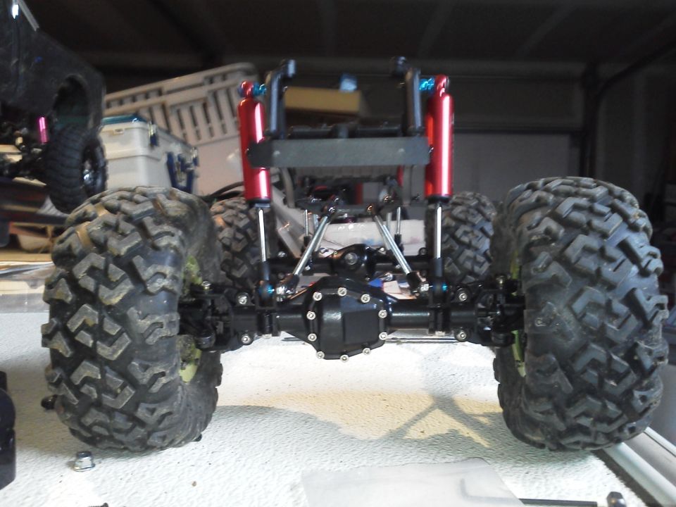 Rear axle and suspension of a remote control monster truck with large tires and red shock absorbers