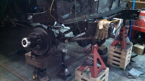 1967 Ford F-250 - Front end of a truck chassis undergoing repairs, supported by red jack stands.