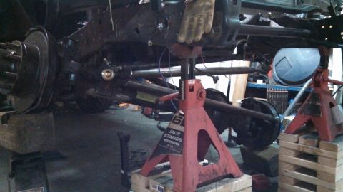 1967 Ford F-250 - The rear axle and frame of a 1967 Ford F-250 are supported by jack stands during a build or repair.