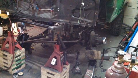 1967 Ford F-250 - Vehicle frame and suspension components are supported by jack stands in a workshop setting.