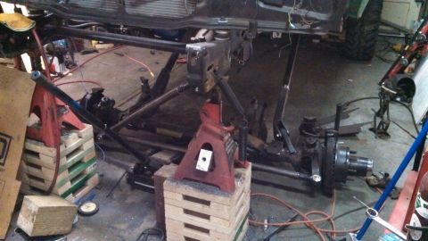 1967 Ford F-250 - The underside of a truck is supported by jack stands as it undergoes maintenance or modification in a workshop.