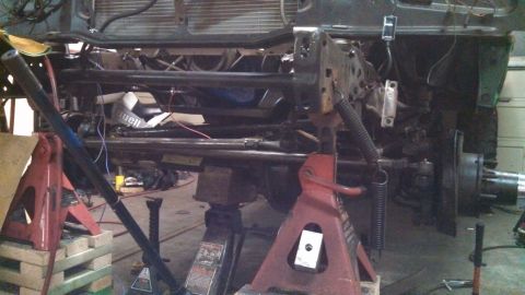 1967 Ford F-250 - The front suspension and frame of a truck are visible, supported by jack stands.