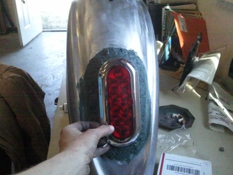 1995 Ford F-150 - A person is fitting a new taillight into a custom-made metal fender, likely for a vehicle modification project vehicle modification project…