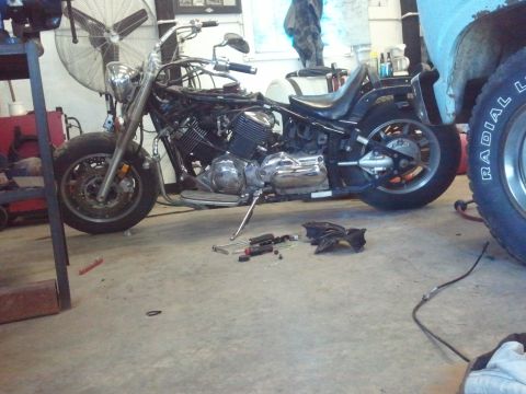 1995 Ford F-150 - A motorcycle is partially disassembled in a garage, with tools scattered around it.