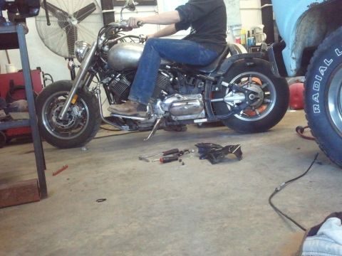 1995 Ford F-150 - A person sits on a motorcycle in a garage with tools scattered around on the concrete floor.